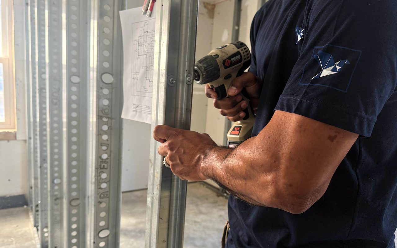 Blue Pigeon technician installing metal stud framing on a commercial interior