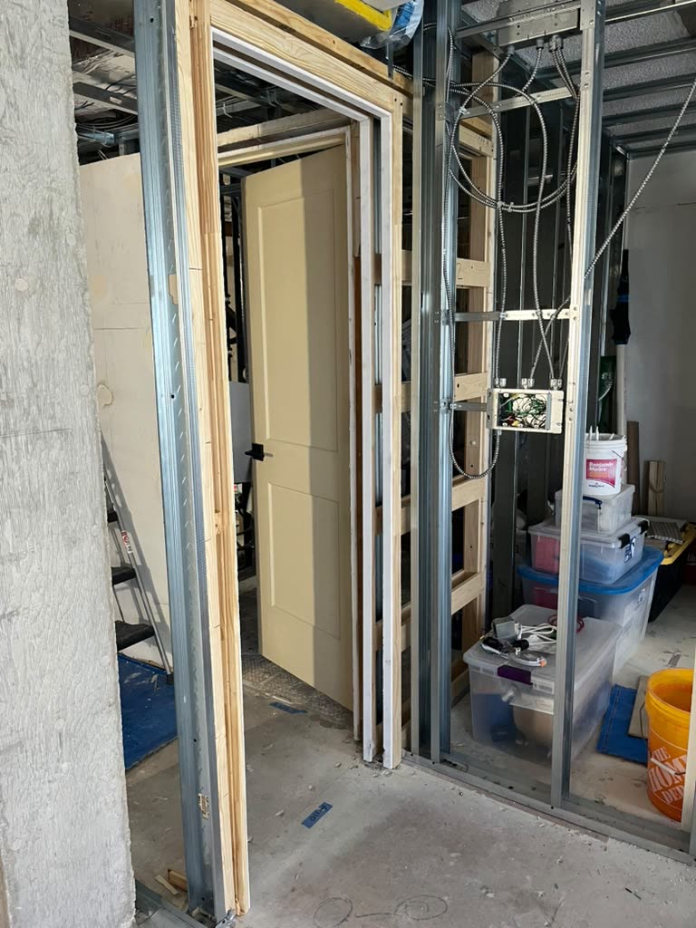 A finished interior door frame with steel and wood stud framing, wiring routed neatly for electrical rough-in.