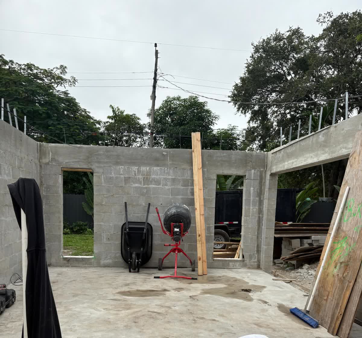 New concrete block addition under construction, with a wheelbarrow and cement mixer staged against the back wall.